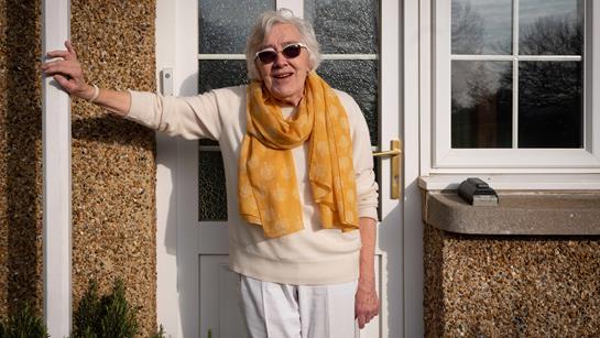 Older Woman Stood Outside Her Home Smiling With Sunglasses On