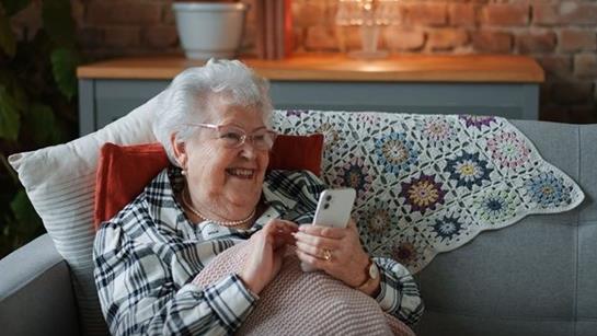 Older Woman Sat On The Sofa Smiling