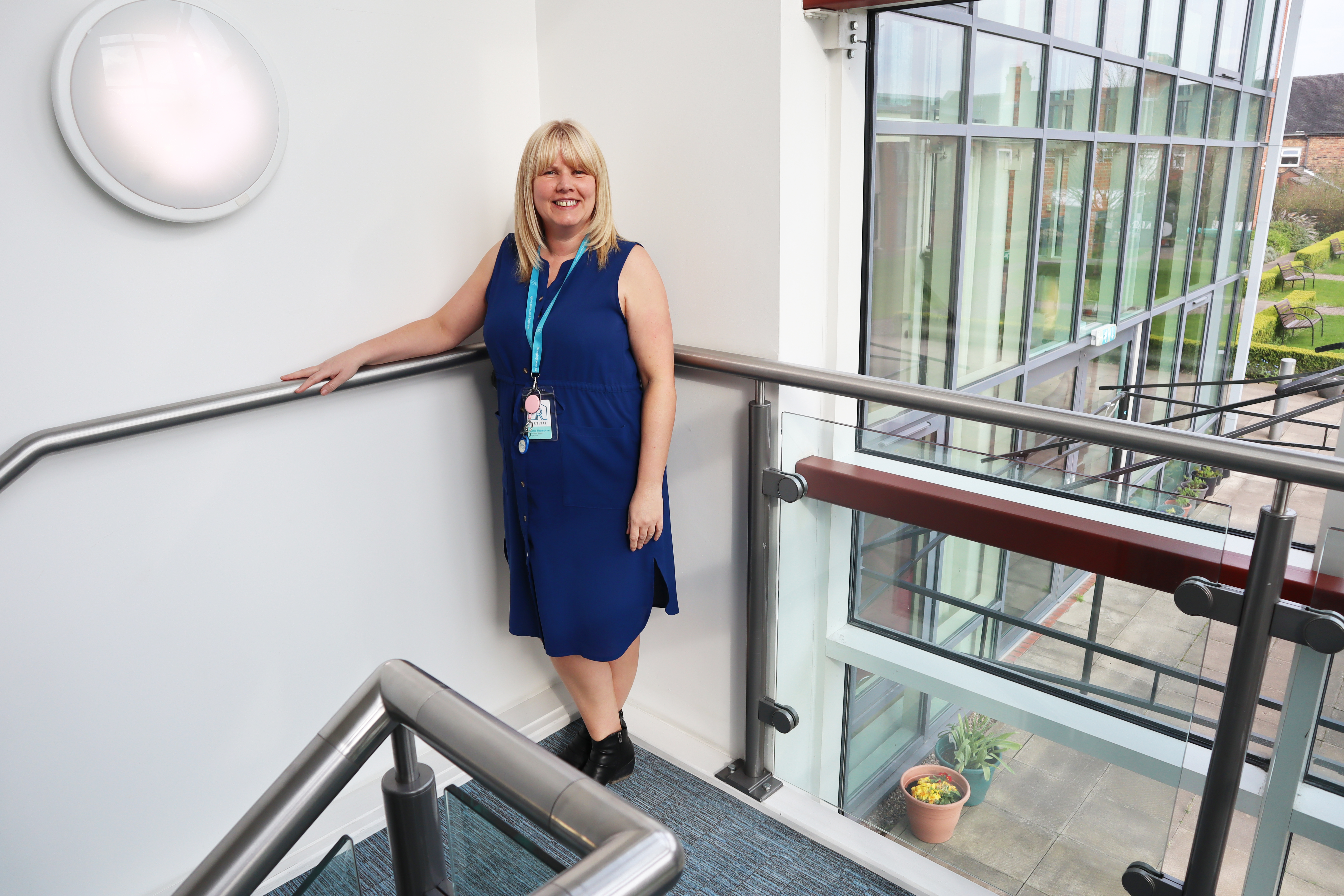 Operations Manager Katie stood at the top of a stairwell, looking at the camera and smiling